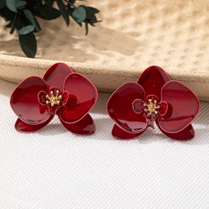 Makroaufnahme der dunkelroten Emaille-Orchideen-Ohrringe mit goldenem Staubblatt
