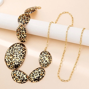 Close-up of golden paperclip chain belt featuring bold leopard print oval charms