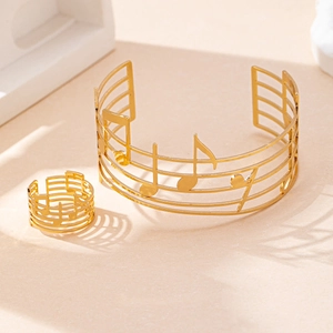 Dettaglio del set di gioielli con note musicali dorate, bracciale rigido e anello coordinato