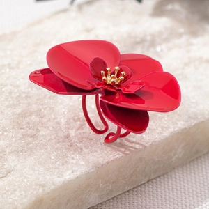 Makroaufnahme: Roter Emaille-Blumenring mit goldener Mitte auf weißem Steinuntergrund