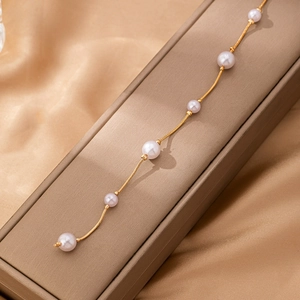 Elegant gold snake chain belt for women with white pearls on a champagne silk background