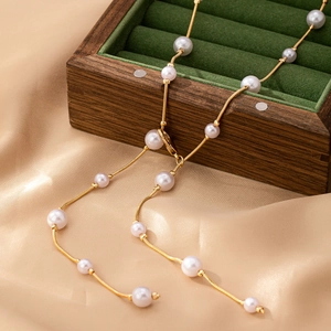 Elegant gold pearl body chain necklace displayed on luxury velvet and silk fabric