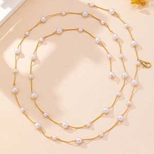 Detail of elegant pearl waist chain featuring gold snake chain and round white pearls