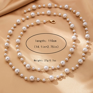 Détail d'une chaîne de corps en perles de 110 cm avec maillons dorés sur soie champagne