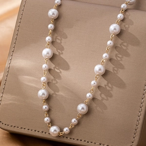 Chaîne de taille élégante en perles blanches et maillons dorés sur un écrin de luxe