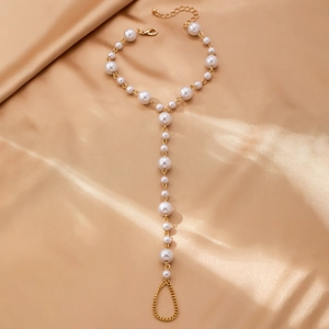 Detailed view of gold baroque pearl toe ring anklet on champagne silk background