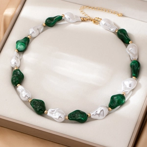 Collana di perle barocche con pietre verdi e accenti dorati in un portagioie di lusso