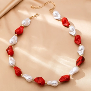 Dettaglio collana di perle barocche con perle in marmo rosso su sfondo di raso dorato