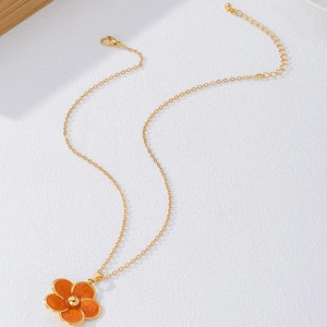 Détail du collier chaîne dorée avec pendentif fleur orange et fermoir mousqueton