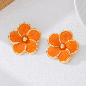 Vue macro des boucles d'oreilles fleurs en émail orange avec une finition dorée