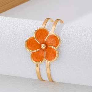 Détail d'un bracelet fleur en émail orange avec finition dorée et perle centrale d'or