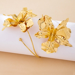Macro detail of glossy golden orchid-shaped metal arm cuff with reflective petals