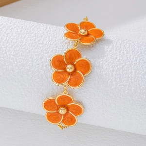 Détail du bracelet fleuri avec pétales en émail orange et perles dorées centrales