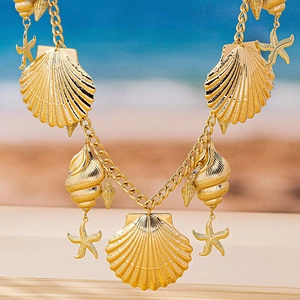 Detail of gold ocean-themed belt featuring oversized sea shells and starfish pendants