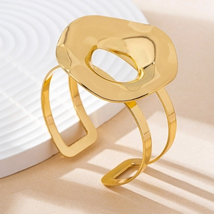 Detailed shot of a minimalist gold hollow geometric bangle on a textured surface