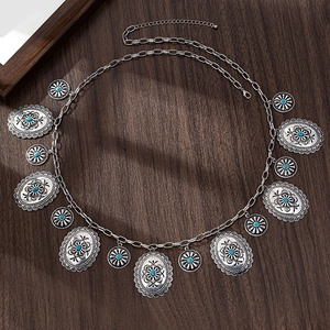Dettaglio di catena da vita boho con pendenti incisi e pietre turchesi decorative