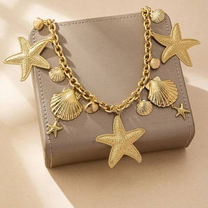 Detail of gold ocean-themed waist chain with starfish and seashell charms on leather