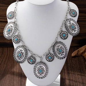 Dettaglio dei pendenti floreali in argento vintage con pietre turchesi su una cintura