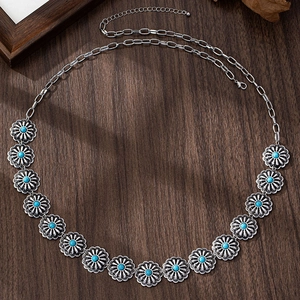 Dettaglio catena in vita boho argento con ciondoli floreali turchesi su fondo in legno