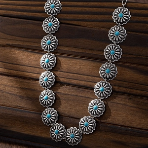 Dettaglio della cintura a catena in argento vintage con fiori turchesi su legno