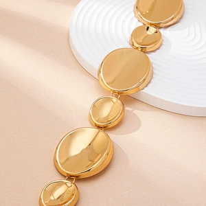 Macro detail of polished gold metal ocean waist chain with mirror finish circular charms