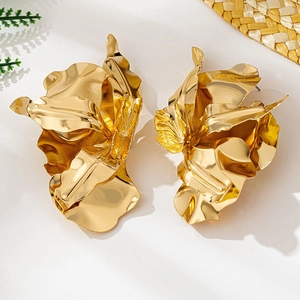 Makroaufnahme großer goldener Blumenohrringe mit Textur auf sommerlichem Hintergrund