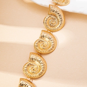 Detailed view of golden conch shells and spiral textures on an ocean style waist chain