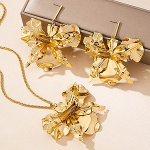 Detailed view of large gold metallic flower earrings and necklace set with petal texture