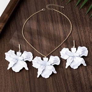 Detail of white 3D flower petal necklace and earring set with gold chain on wood