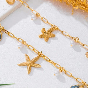 Close-up of golden ocean-themed chain with starfish, shell charms and pearls for women
