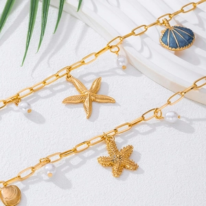 Detailed close-up of golden sea star and shell charms with pearls on an ocean-style chain