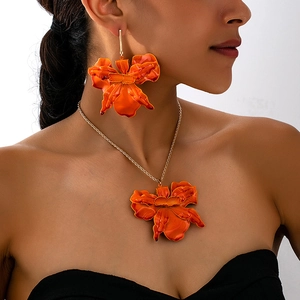 Detail view of the vibrant orange floral necklace and oversized earring set on model