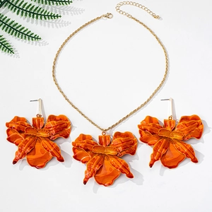 Detailed macro view of vibrant orange orchid jewelry set including necklace and earrings