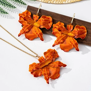 Detailed close-up of orange orchid jewelry set with glossy enamel texture and gold chain