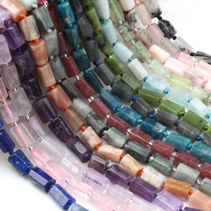 Macro shot of assorted cylindrical natural stone beads showing lapis lazuli and quartz texture