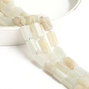 Macro view of polished cylindrical moonstone beads on a white ceramic display