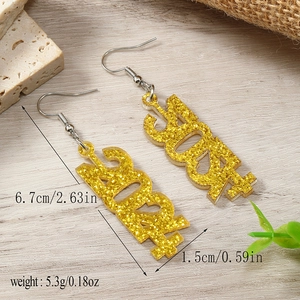 Detailed view of 2024 number earrings with gold glitter and dimensions on wooden background