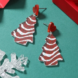 Détail de boucles d'oreilles sapin de Noël avec cœurs rouges sur fond festif vert