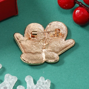 Close-up of golden Christmas glove brooch back with metal pin and textured finish