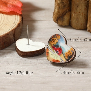 Detalle de pendientes de madera en forma de corazón con estampados otoñales