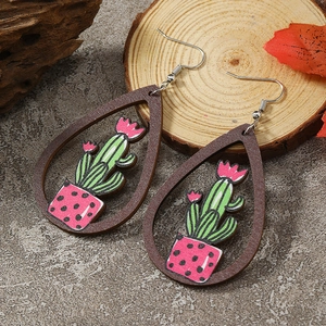 Macro detail of teardrop wooden earrings featuring green cactus and pink pot patterns