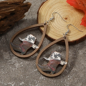 Detail of teardrop wooden earrings featuring western cowboy boots and cow print pattern