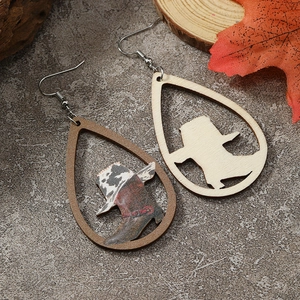 Detail of wooden teardrop earrings featuring western cowboy boot cutouts on stone surface