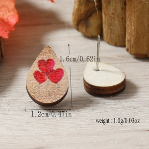 Detalle de pendientes de madera en forma de gota con corazones rojos y pernos