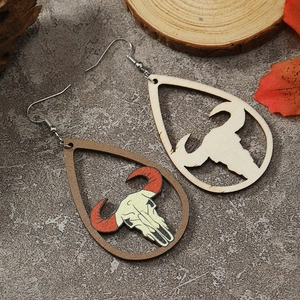 Detailed close-up of bohemian teardrop wood earrings with bull skull motifs and silver hooks