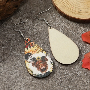 Detail der Tropfenohrringe aus Holz mit Kuh- und Sonnenblumenprint im Western-Stil