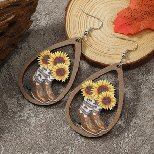 Detail of teardrop wooden earrings with sunflower and cowboy boot print on rustic wood