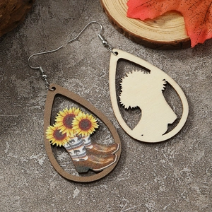 Detail of wooden teardrop earrings featuring sunflower and cowboy boot print on textured background
