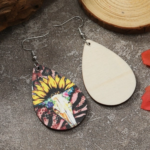 Details von Tropfenohrringen aus Holz mit Sonnenblumen- und Totenkopf-Print auf Stein