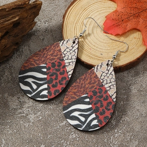 Close-up of teardrop earrings with mixed animal prints on a wooden display stand